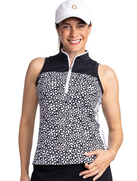 Close front view of a smiling woman wearing the Resolution Sleeveless Golf Top in Fall Bloom print and the We've Got You Covered Hat in White. This top consists of a black yoke, fall bloom print on the bodice, a white stripe with black stitching on each s