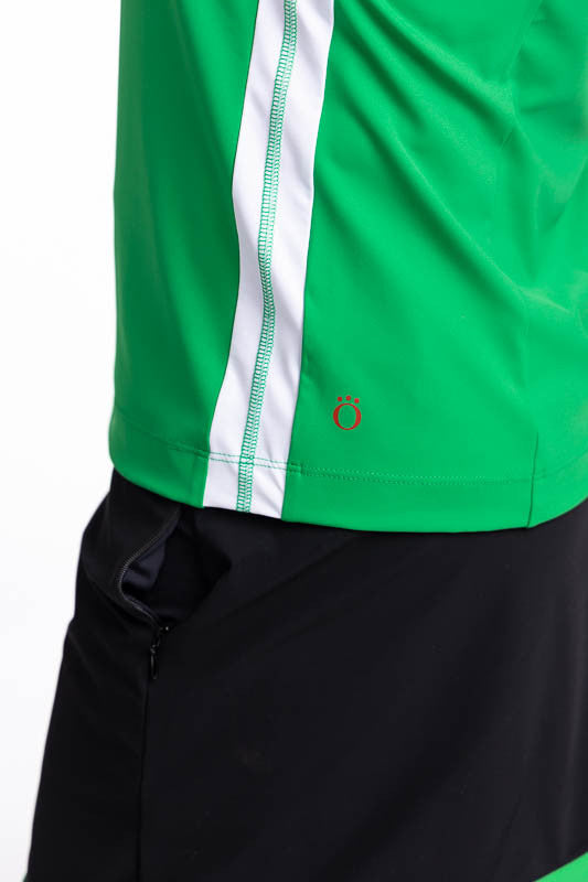 Close left side view showing the hemline on the Resolution Sleeveless Golf Top in Rye Grass Green. This top has a white yoke, rye grass green body, a white stripe down each side and black trim around the collar, front quarter zipper, and around each armho