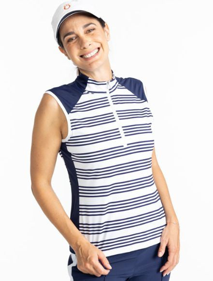 Smiling woman wearing the Cap to Tap Short Sleeve Golf Top in Shutter Stripe and the We've Got You Covered Hat in White. This shirt has solid navy blue triangles on each shoulder as well as a solid navy blue section on each side of this top along with hor