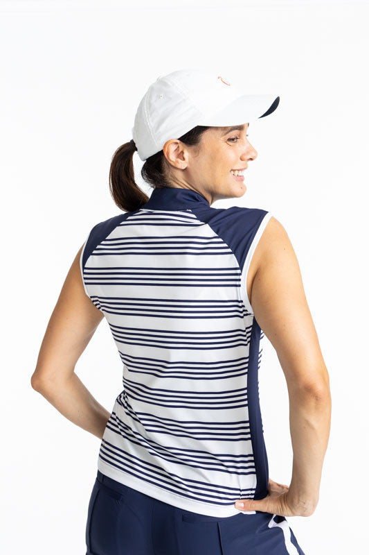 Back view of the Cap to Tap Short Sleeve Golf Top in Shutter Stripe and the We've Got You Covered Hat in White. This shirt has solid navy blue triangles on each shoulder as well as a solid navy blue section on each side of this top along with horizontal s