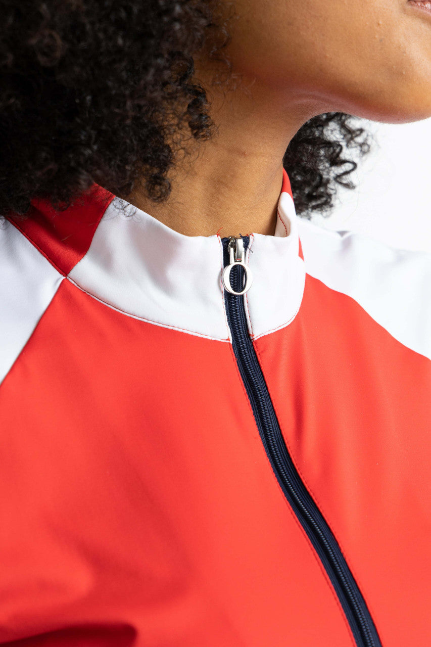 Close front view of the neckline and zipper on the Cap to Tap Short Sleeve Golf Top in Tomato Red. In this view. you can see the solid, rectangular sections on either side of the front zipper as well as the navy blue quarter zip zipper.