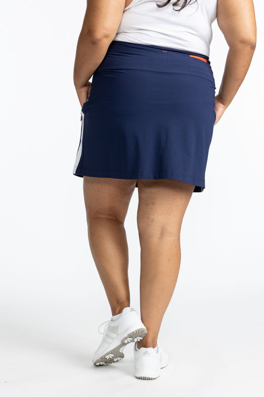 Back view of the Party Pleat Golf Skort in Navy Blue. This skort has a solid, white stripe that runs down each side of this skort. 