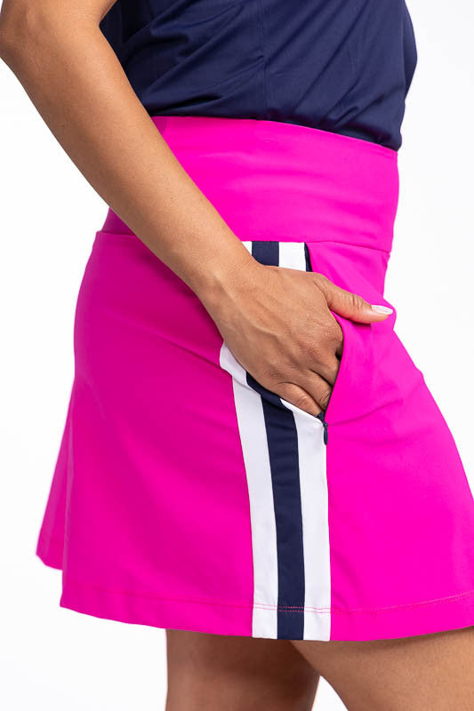 Close right side view of one of the zippered, in-seam pockets on the Party Pleat Golf Skor tin Open Air Pink. This is a bright pink skort with white and navy blue trim on each side. It also features two in-seam, zippered pockets with built-in tee holders 