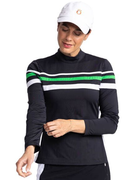 Front view of a woman wearing the Winter Rules Long Sleeve Golf Top in Black and the We've Got You Covered Hat in White. This top features three alternating stripes of white, rye grass green, and white stripes on a black long sleeve top with one white str