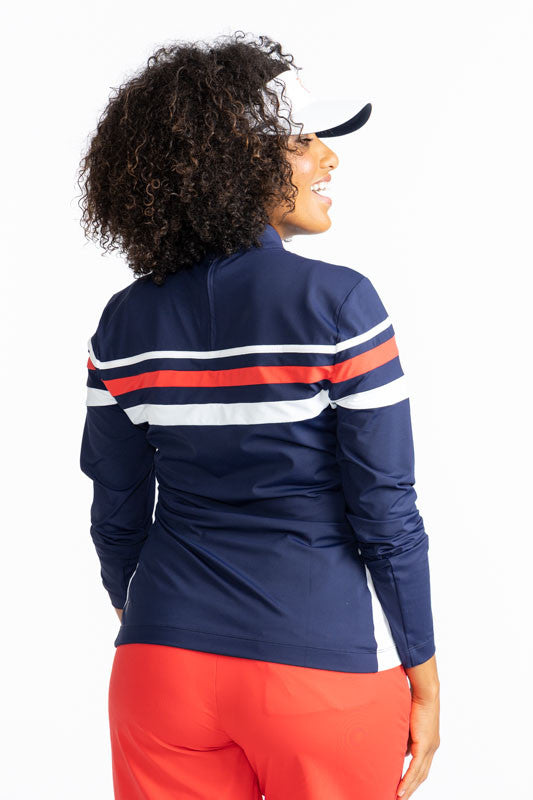 Back view of the Winter Rules Long Sleeve Golf Top in Navy Blue. This shirt is primarily navy blue with a 360 degree pattern of lines across the chest area. A thin, white stripe followed by a spacer of navy blue, then a thicker, solid tomato red stripe fo