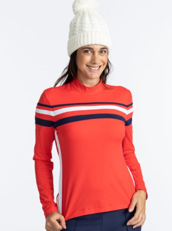 Smiling woman wearing the Winter Rules Long Sleeve Golf Top in Tomato Red. This top is primarily tomato red with a 360 degree pattern of lines across the chest area. A thin, navy blue stripe followed by a spacer of tomato red, then a thicker, solid white 