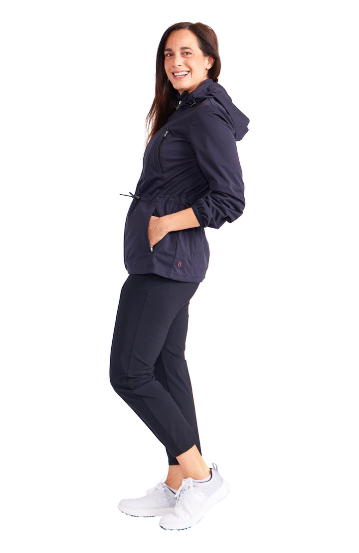 Side view of woman wearing black hooded golf rain jacket with cinch and black pants