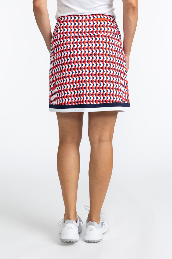 Back view of the On The Fringe Golf Skort in Chevron Tomato Red. This pattern consists of red, white, and blue chevrons with two solid stripes at the bottom of the skort - a solid navy blue stripe and a solid white stripe.