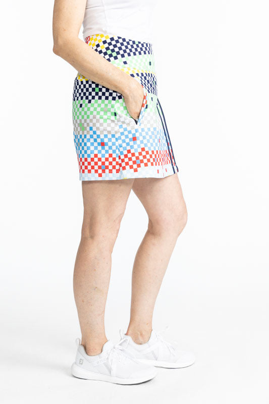 Full right side view of the Skort and Short Golf Skort in Cheeky Check print. This print is made up of a checked horizontal patter that creates a horizontal wrap in black, grass green, lemon yellow, French blue, and tomato red on a white background. This 