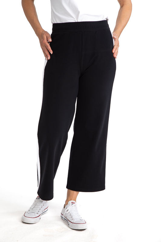 Front view of the Apres 18 Wide Leg Pants in Black. These pants have a single, white stripe that runs down each side.