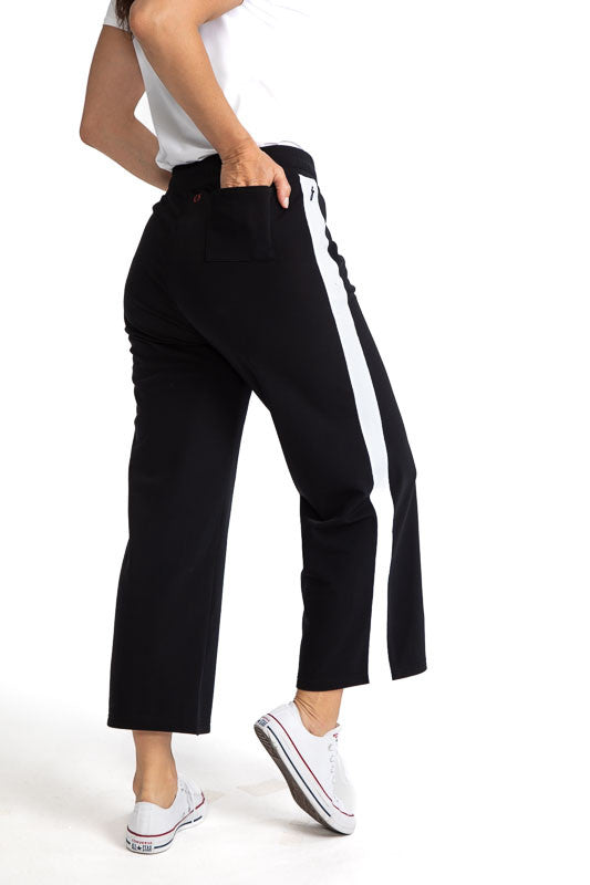 Back and right side view of the Apres 18 Wide Leg Pants in Black. These pants have a single, white stripe that runs down each side.