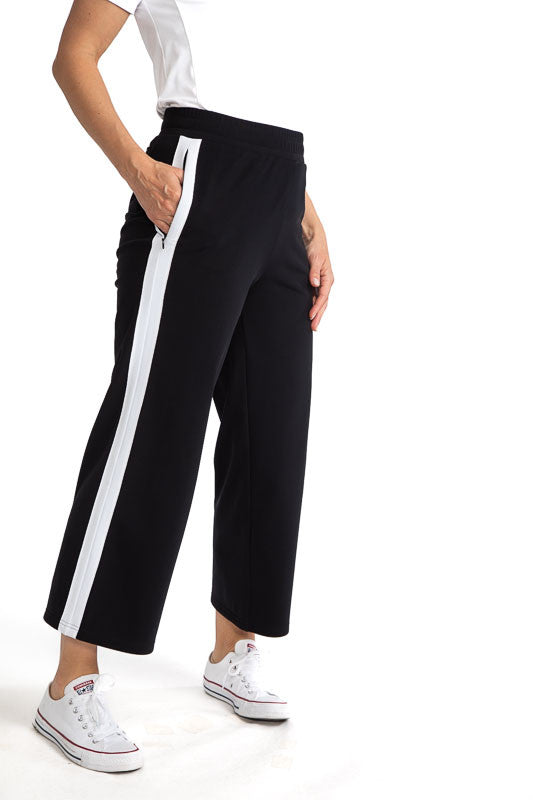 Right side view of the Apres 18 Wide Leg Pants in Black. These pants have a single, white stripe that runs down each side.