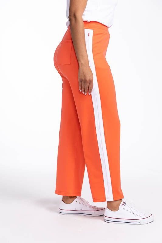 Right side version showing the white stripe up the leg on the Aprés 18 Wide Leg Pants in Coral Red. These are a solid coral red pants with one white stripe up each leg.