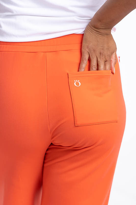 Close back view of the patch pocket on the right side of the Aprés 18 Wide Leg Pants in Coral Red. These are a solid coral red pants with one white stripe up each leg.