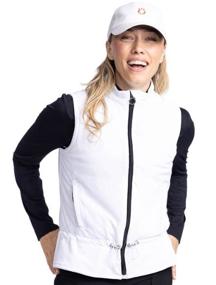 Front view of a smiling woman wearing the Layer Slayer Golf Vest in White, the Lovely Layer Long Sleeve Golf Top in Black, and the We've Got You Covered Hat in White.