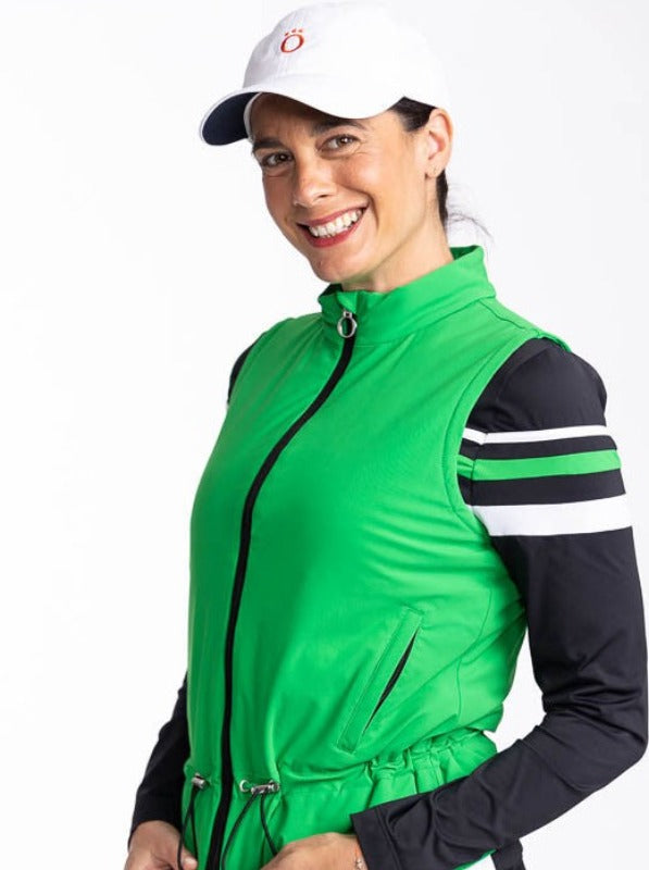 Front view of a smiling woman wearing the Layer Slayer Vest in Rye Grass Green, the Winter Rules Long Sleeve Top in Black, and the We've Got You Covered Hat in White.