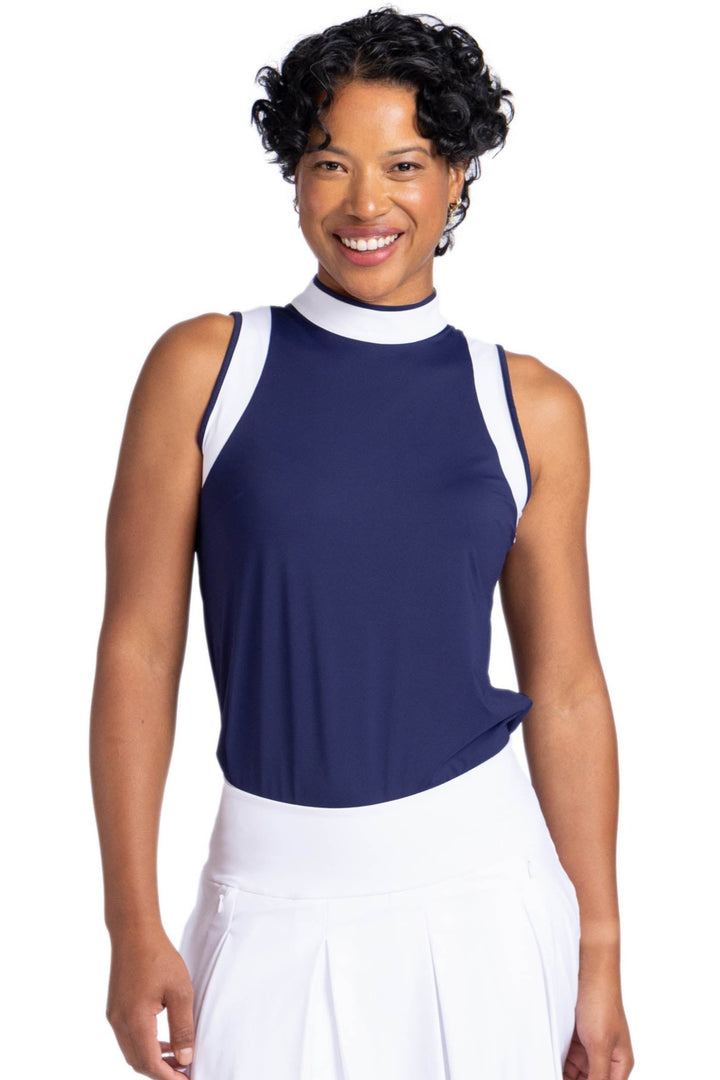 Front view of a woman wearing the Knock Out top in navy blue; a sleeveless top with white contract panels on the armholes and around the neckline. 