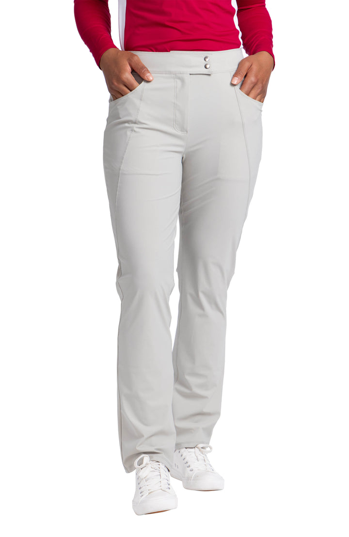 A woman wearing the Clum Compliant pant in neutral sand with her hands in the front pockets.