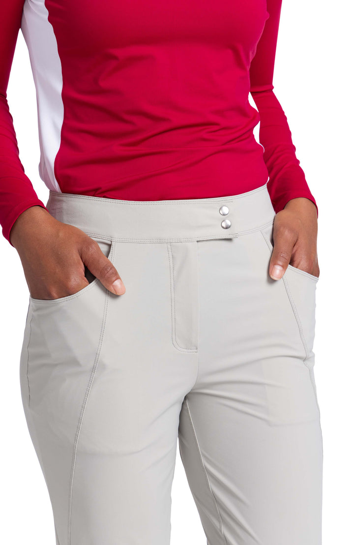 Close detail view of a woman with her hands in the front pockets of the Club Compliant pant. The waistband features a n overlap two snap waistband.   