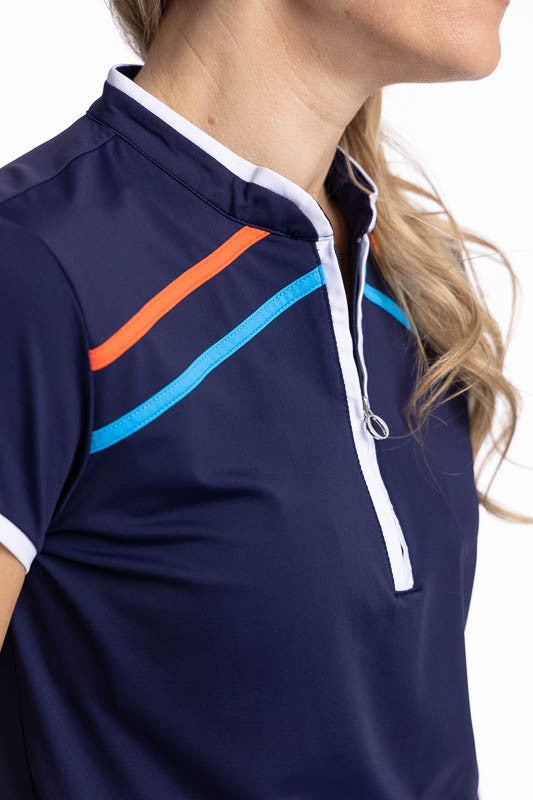 Close front view of the collar and neckline on the Gimme Putt Short Sleeve Golf Top in Navy Blue and the We've Got You Covered Hat in White. The Gimme Putt top is a solid navy blue top with  two diagonal stripes on either side of the front quarter zip - o
