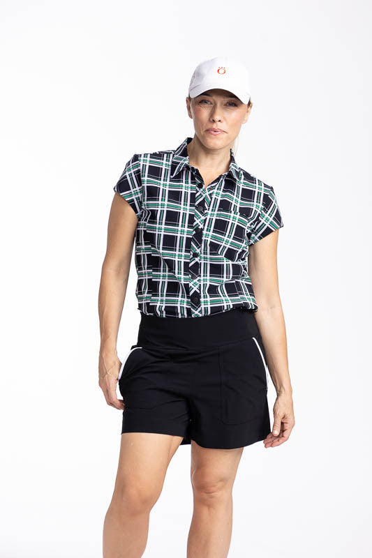 Front view of a woman wearing the Tough in the Rough Short Sleeve Golf Top in Tartan Plaid, the Carry My Cargo Golf Shorts in Black/White, and the We've Got You Covered Hat in white.