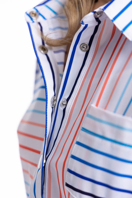 Close front view of the snap front closure and collar on the Tough in the Rough Short Sleeve Golf Top in Sun Stripe print. The Sun Stripe print consists of a mix of horizontal and vertical stripes in coral red, pacific blue, and navy blue on a white backg