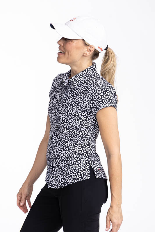 Left side view of a woman wearing the Tough in the Rough Short Sleeve Golf Top in Fall Bloom print and the We've Got You Covered Hat in white.