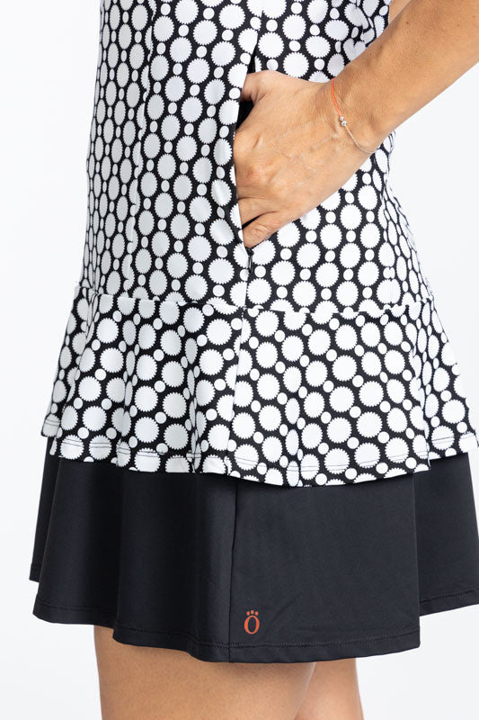 Close left side view of one of the pockets and the hemline on the On In Two Sleeveless Golf Dress in Spiral Floral print. This is a retro style black and white print with a large, solid black section at the base of the dress.