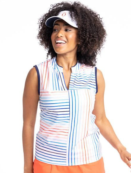 Close front view of a smiling woman wearing the Sandy Par Sleeveless Golf Top in Sun Stripe Print and the No Hat Hair Visor in White. The print consists of a mix of horizontal and vertical stripes in coral red, pacific blue, and navy blue on a white back 