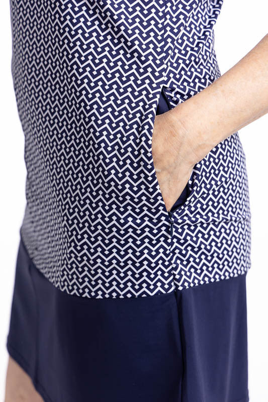 Close left side view of one of the zippered in-seam pockets on the Sandy Par Sleeveless Golf Dress in Chic Chevron print. The print consists of white chevrons on a navy blue background. The low-banded collar and armholes are trimmed in navy blue, and the 