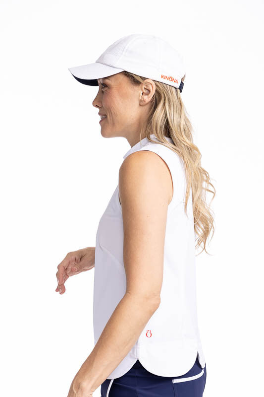 Left side view of the On The Edge Sleeveless Golf Top in White and the We've Got You Covered Hat in White. This top features a back zipper and a feminine scallop design along the hemline.