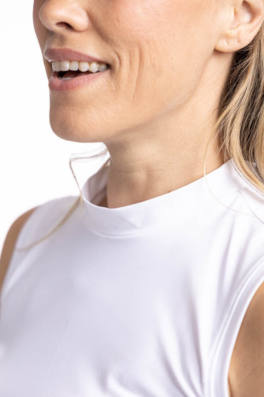 Close front view of the neckline on the On The Edge Sleeveless Golf Top in White and the We've Got You Covered Hat in White. This top features a back zipper and a feminine scallop design along the hemline.