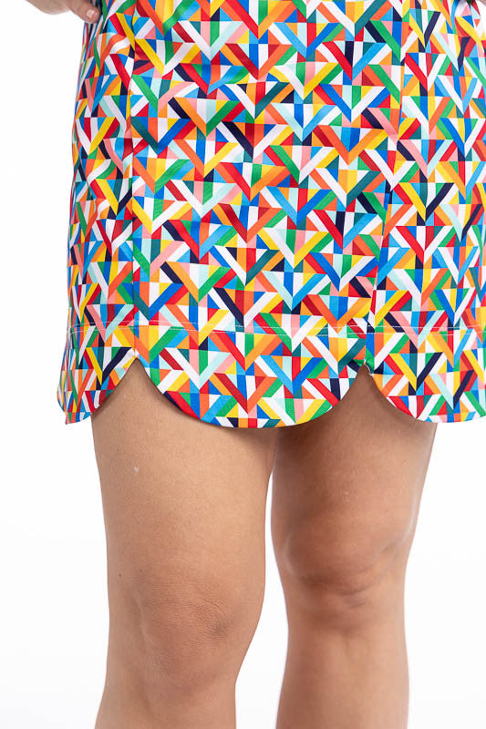 Close front view of the scalloped hemline on the On The Edge Sleeveless Golf Dress in K All Day print. The K All Day print is an abstract confetti-style mirrored K-shaped pattern in red, orange, yellow, green, blue, black and white.