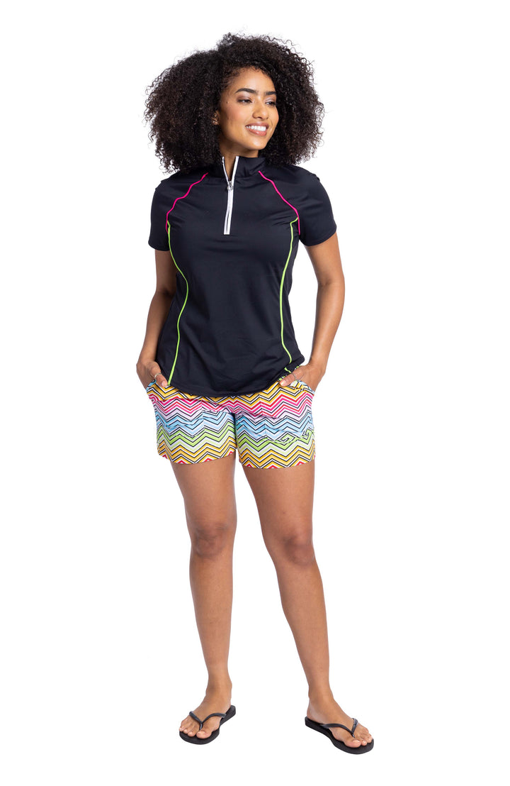 Woman's black golf shirt with pink and yellow piping and multicolored shorts