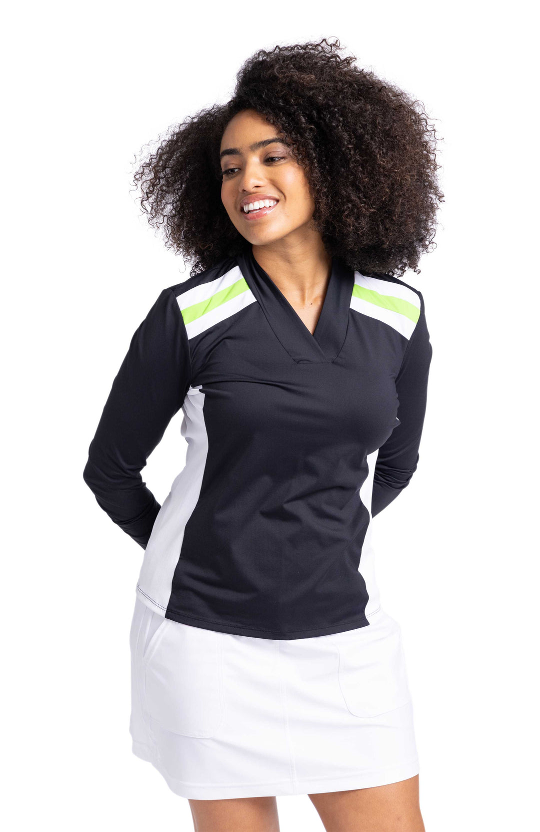 Woman smiling wearing a black longsleeve top with white and green stripes on shoulders and white contrasting side panels. She's also wearing a white skort. 