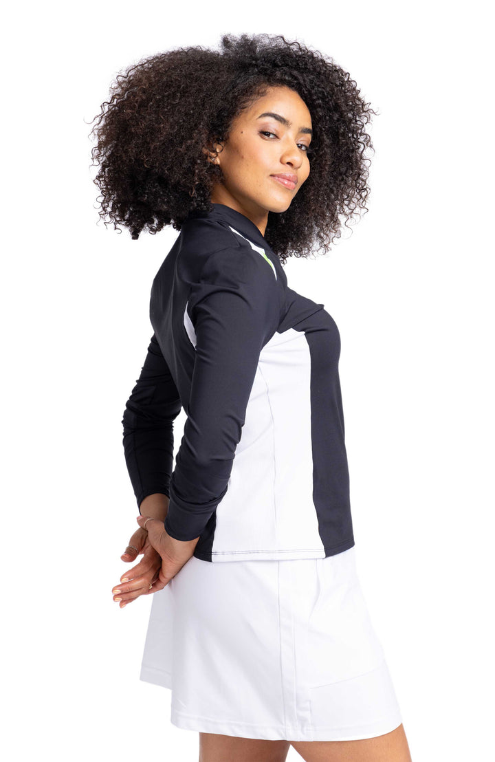 Side view of a woman wearing a black longsleeve top with white contrasting side panel.