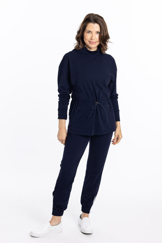 Full front view of a woman wearing an Apres 18 Anorak Longsleeve Hoodie in navy blue and a pair of Apres 18 Jogger pants in navy blue