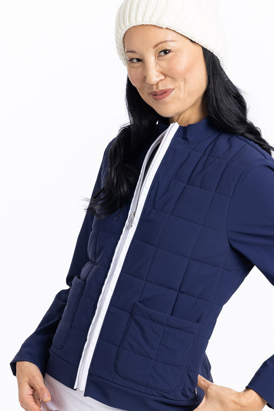 Smiling woman wearing a navy blue Quilted and Cozy Jacket and a white knit cap