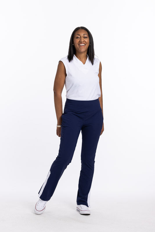 Smiling woman wearing a Light and Lovely sleeveless golf top in white and Snappy Golf Trouser Pants in navy blue