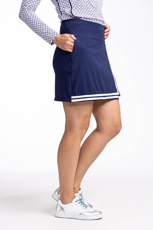 Right side view of the No Break Golf Skort in Navy Blue. This is a navy blue skort with two white stripes that run in an "L" shape from the top left side down to the hemline and to the right. It features a faux wrap front with a layer beneath and built-in