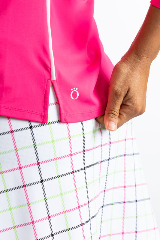 Close left side view of the hemline on the Keep It Covered Long Sleeve Golf Top in Preppy Pink. This is a solid pink top with a white 1/4 zip in the front and two thin, white stripes down each side.