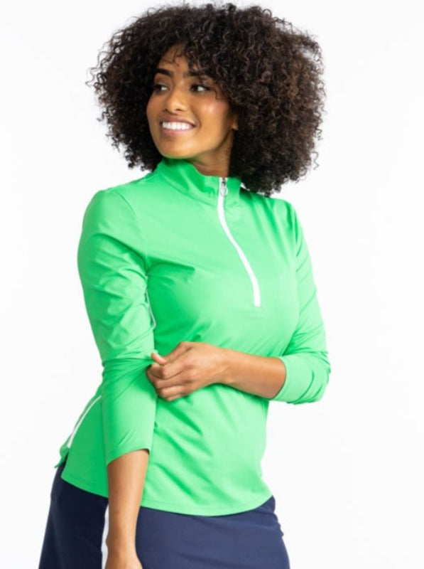 Smiling woman wearing the Keep It Covered Long Sleeve Golf Top in Kelly Green. This top also has a white quarter zip zipper on the front and two thin, solid white lines on each side. 