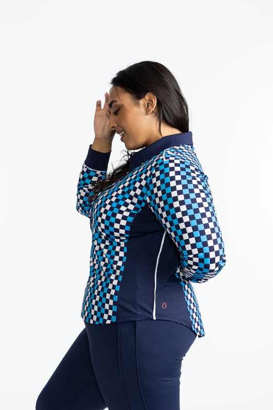 Left side view of the At The Pin Long Sleeve Golf Top in Check It Out print. This print is a mix of French blue, black, and white checks forming a vertical striped pattern. This shirt features a solid navy blue collar, a five button front with white butto