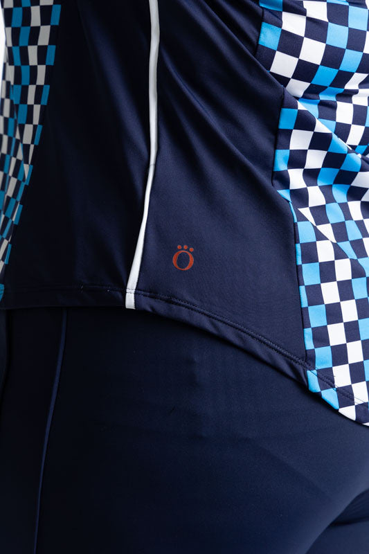 Close left side view of the solid navy blue section with a single thin, white stripe on each side of the At The Pin Long Sleeve Golf Top in Check It Out print. This print is a mix of French blue, black, and white checks forming a vertical striped pattern.