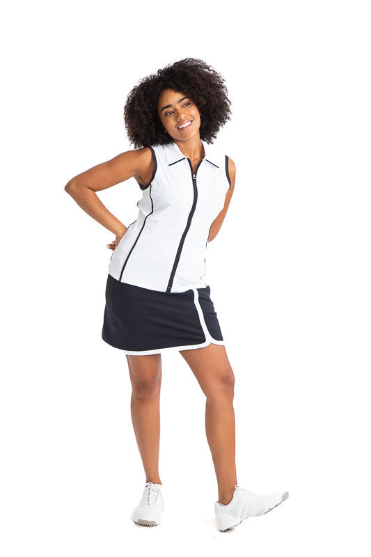 Full front view of a woman golfer wearing the Swing Away Sleeveless Golf Top in White and the Simply Sassy Golf Skort in Black. This top has black accents down the front zipper,  around each sleeve, and two stripes on each side. 
