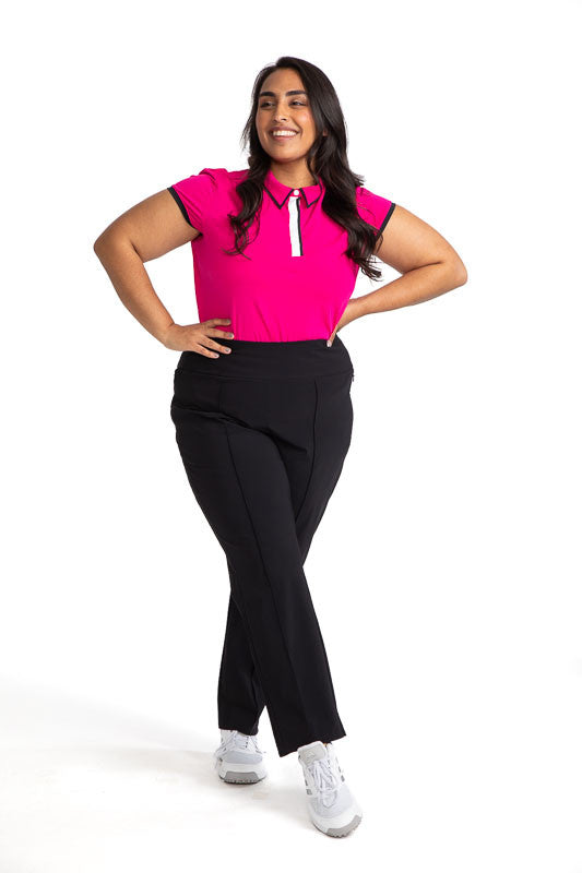 Full front view of a woman golfer wearing the Up and In Short Sleeve Golf Top in Magenta Pink and the Smooth Your Waist Crop Pants in Black.