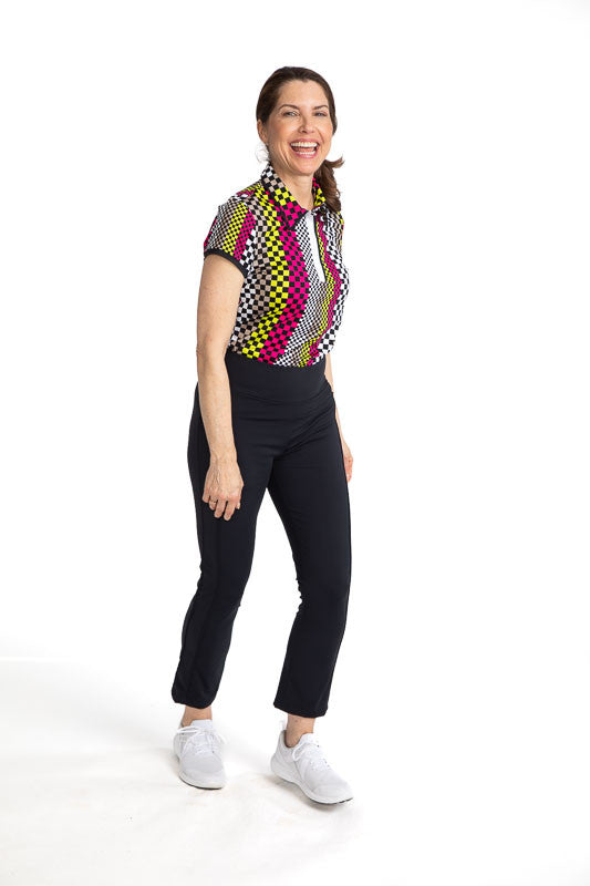 Full front view of a smiling woman golfer wearing the Up and In Short Sleeve Golf Top in Checks Mix print and the Smooth Your Waist Crop Golf Pants in Black.