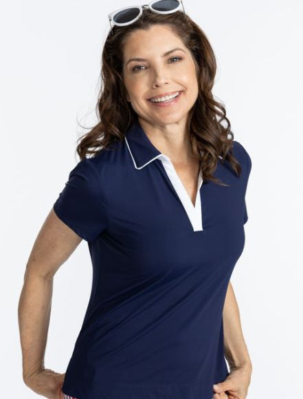 Smiling woman wearing the Classic and Fantastic Short Sleeve Golf Top in Navy Blue. There are also white accents on the edge of the collar and the v-neck on this top.