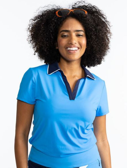 Front view of a smiling woman wearing the Classic and Fantastic Short Sleeve Golf Top in French Blue. This top is a solid French blue with a navy blue collar trimmed with white and a navy blue V-neck front.