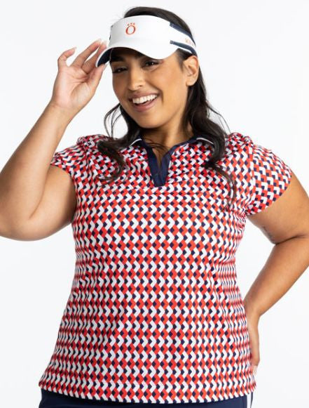 Smiling woman wearing the Classic and Fantastic Short Sleeve Golf Top in Chevron Tomato Red and the No Hat Hair Visor in White. This top has a navy blue collar and v-neck with white trim on the edge of the collar.